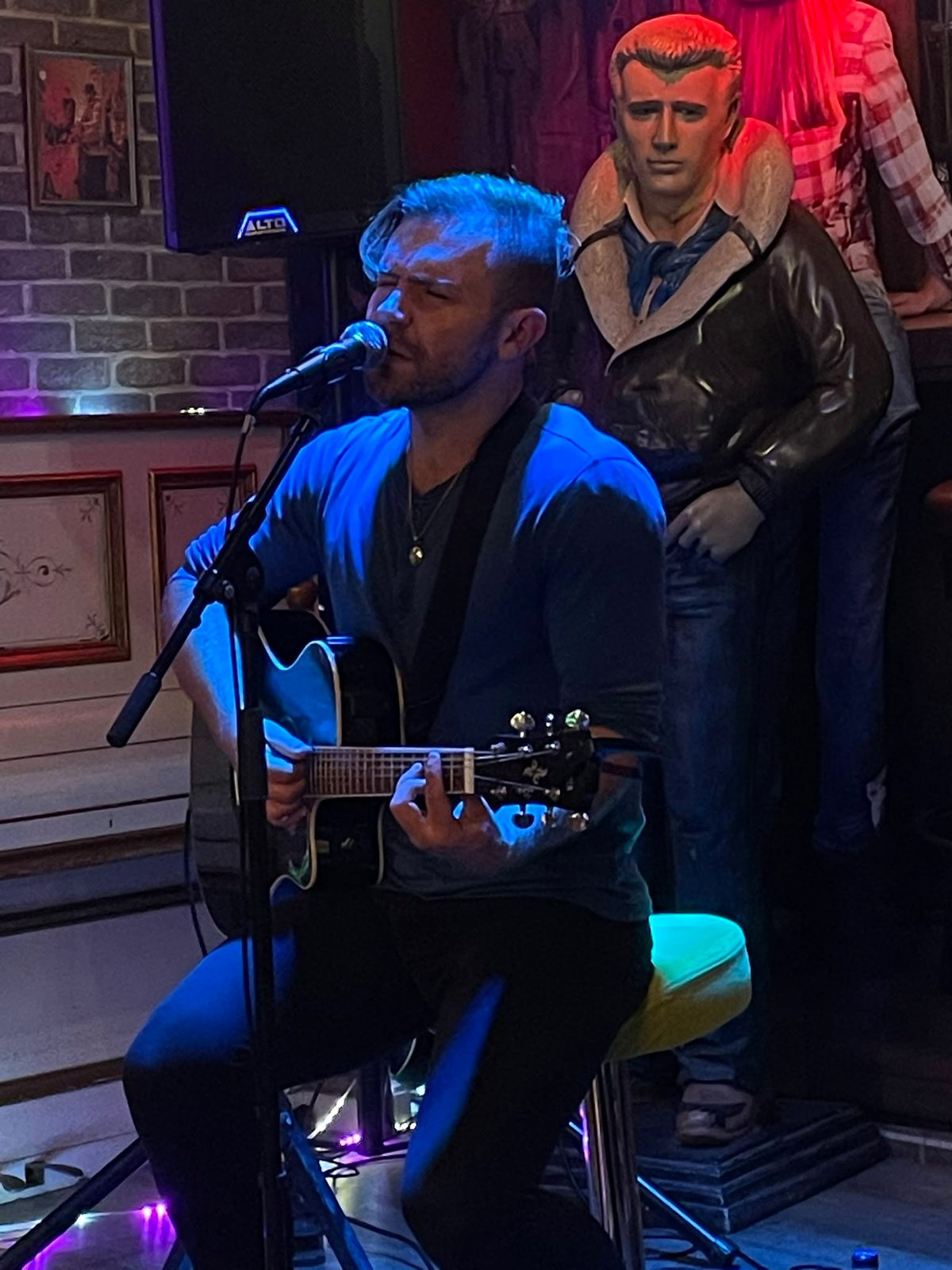 Zack seated with guitar and microphone